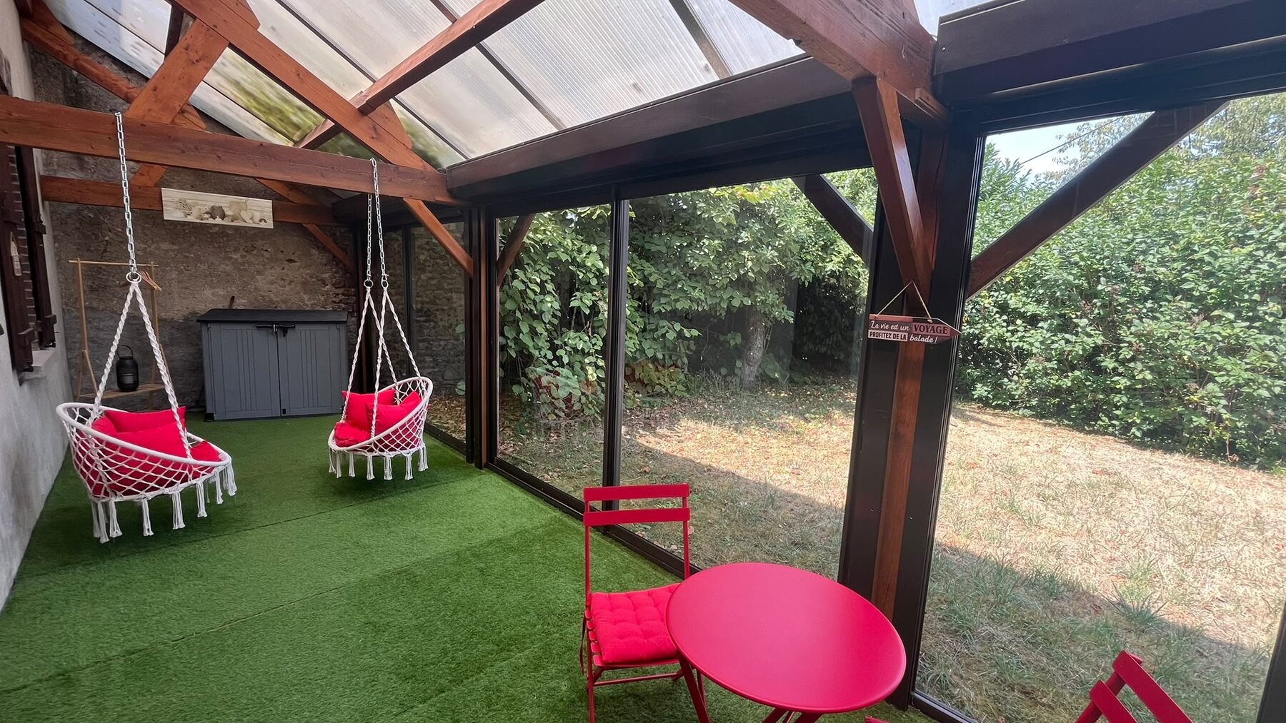 Véranda avec fauteuils suspendus, ouverte sur le jardin